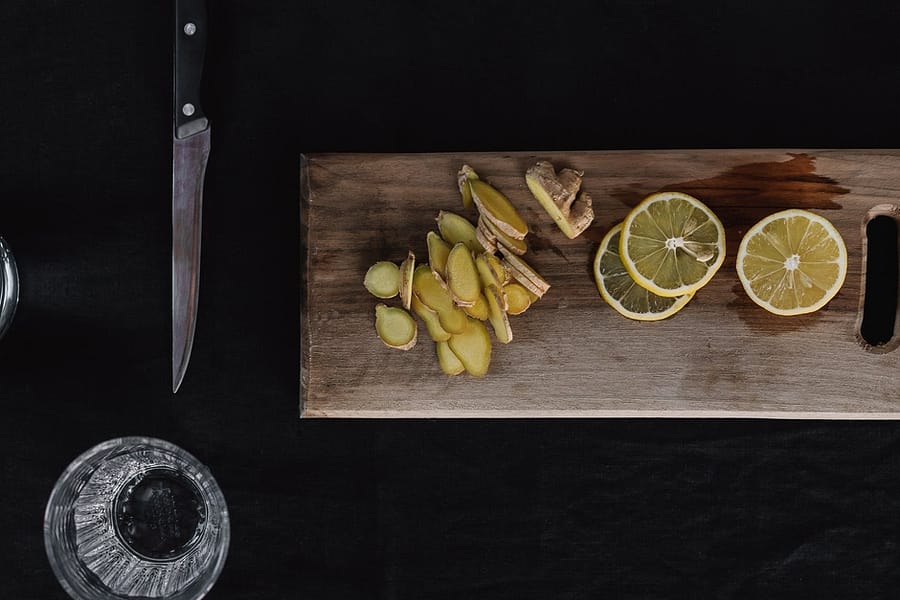 sliced ginger and lemons on wooden chopping board
